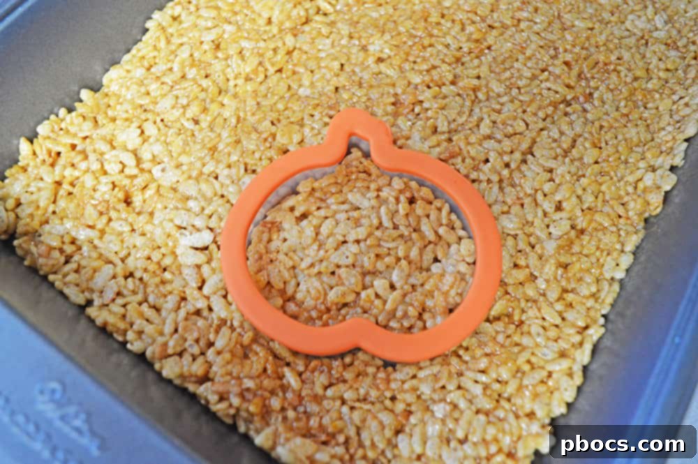 Perfectly pressed pumpkin Rice Krispie treats cooling in a pan, viewed from above.