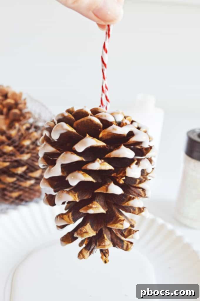 A pine cone being dipped into a plate of white glue, preparing it for glitter application.