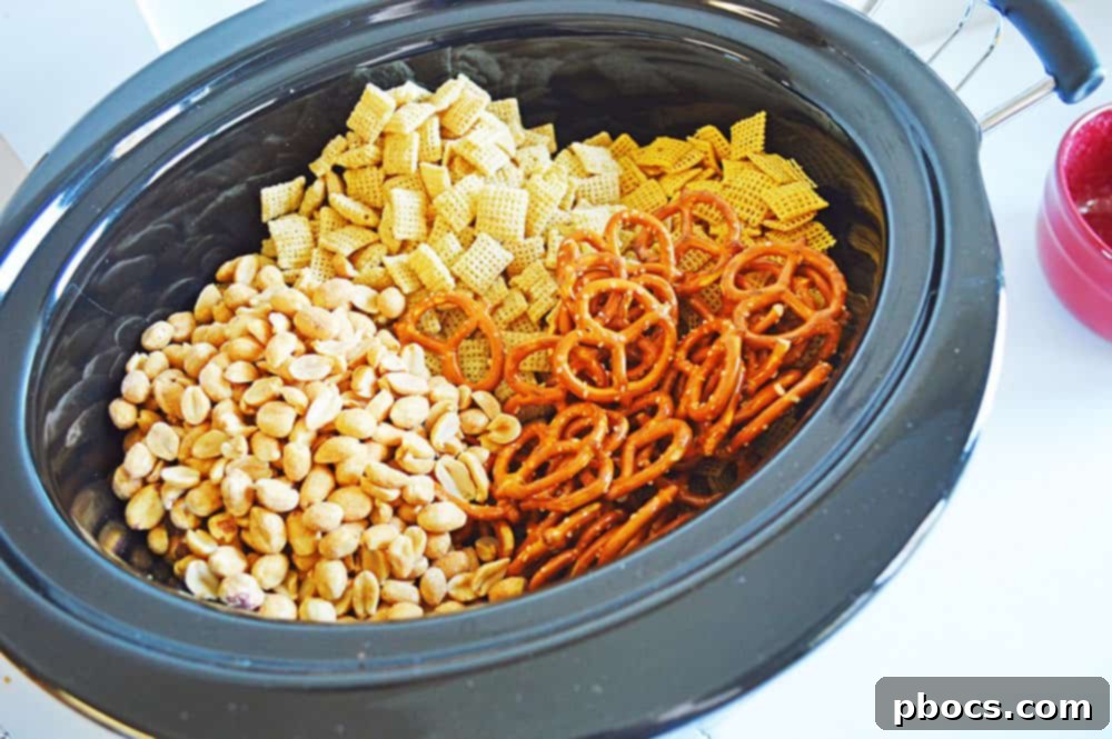Irresistible Slow Cooker Chex Mix 4 Rice Chex, Corn Chex, pretzels, and peanuts in a large crockpot.