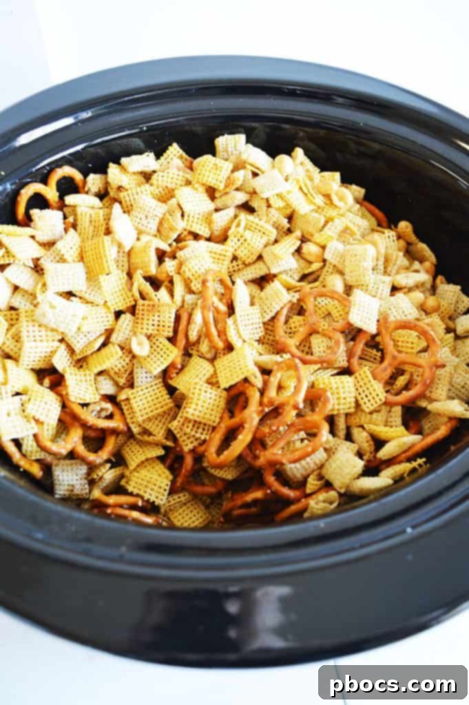 Irresistible Slow Cooker Chex Mix 8 Chex Mix cooking in a slow cooker, being stirred to prevent burning.
