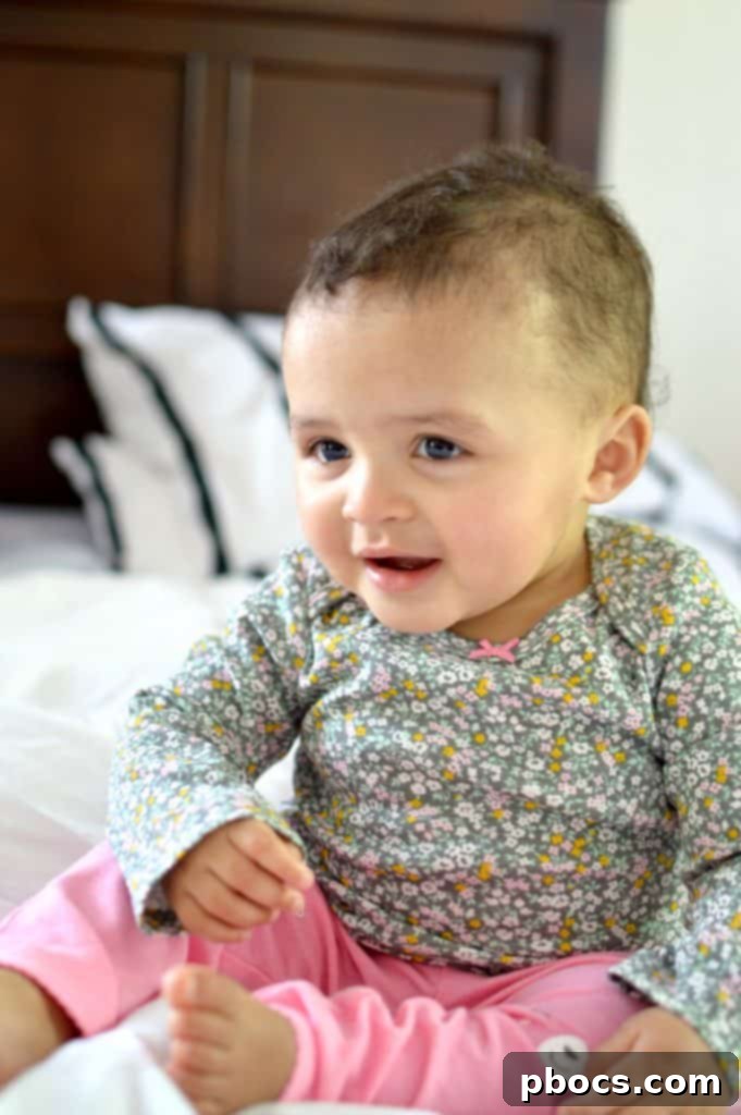 Lauren sitting upright on a plush rug, looking curious and engaged, showcasing the freedom of movement in her Carter's baby clothes.