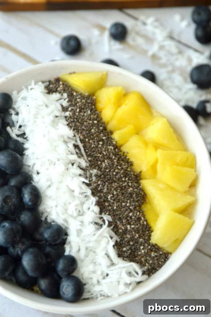 Tropical Dream Banana Pineapple Bowl 2 Close-up of a delicious Banana Pineapple Smoothie Bowl, garnished with blueberries, coconut flakes, and chia seeds for texture