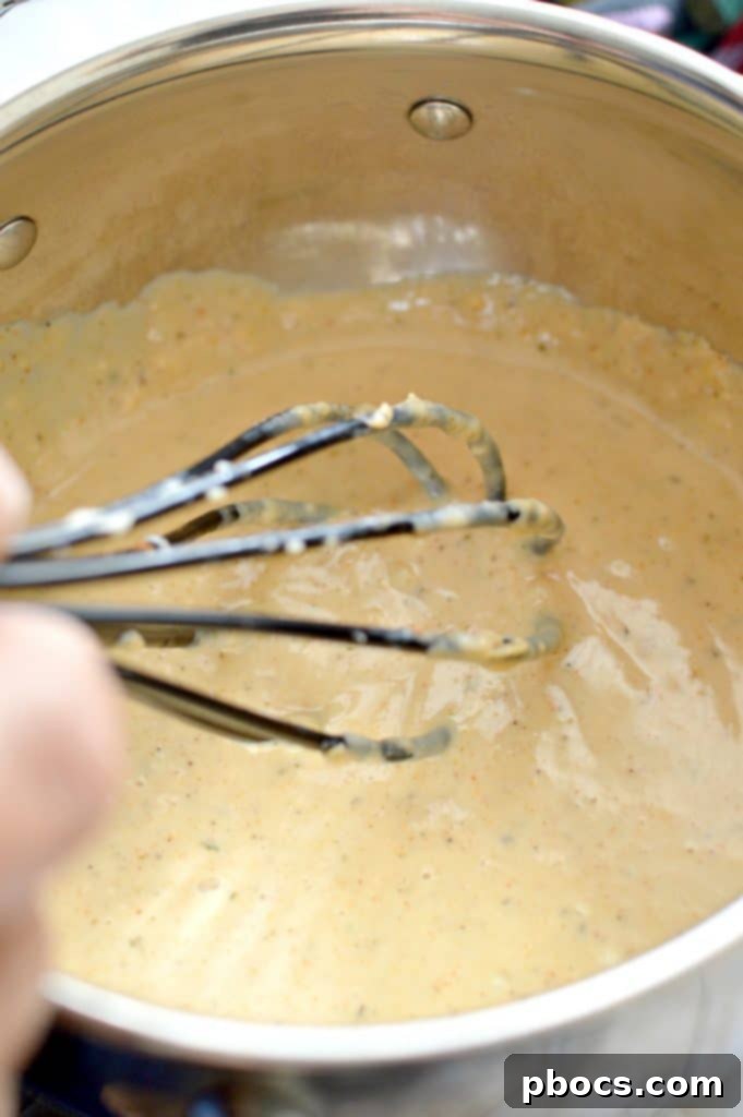 Creamy Skinny Cajun Alfredo sauce simmering gently in a large pan, ready for the pasta and shrimp.