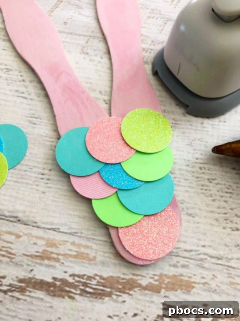 Easy Mermaid Tail Craft Gluing mermaid scales onto the tail frame, starting from the bottom